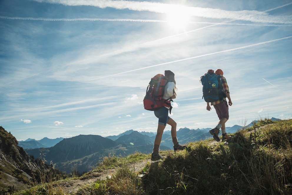 Zwei Menschen wandern im Sonnenschein in den Bergen