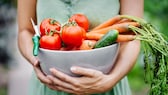 Frau hält Gemüsekorb in ihren Armen