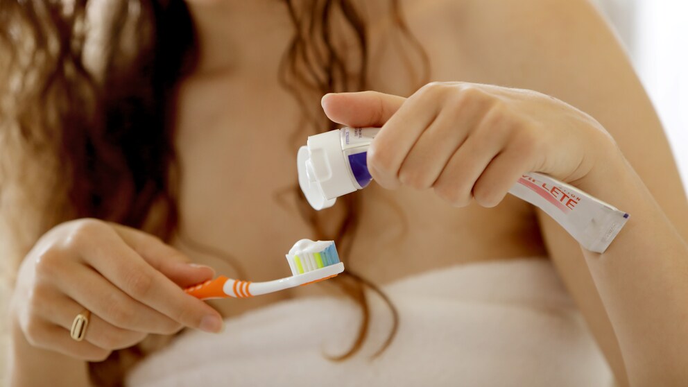 Frau trägt Zahncreme auf