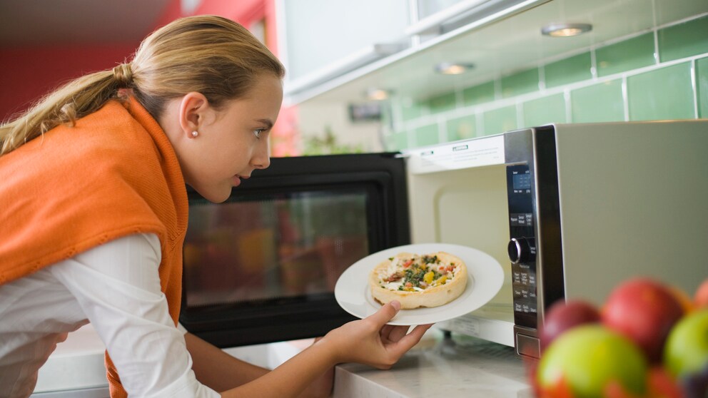 Frau bedient Mikrowelle