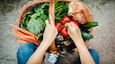 Ernährungs-Quiz: Frau holt Tomaten aus Obstkorb