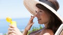 Eine Frau mit Hut und Sonnencreme auf einer Liege