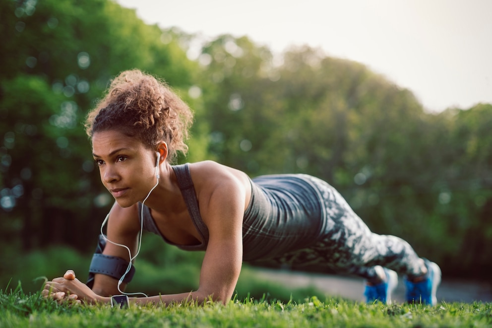 Isometrisches Training: Frau macht Planks im Park