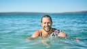 Mann mit Bart schwimmt im Meer