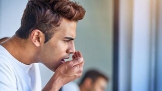 Ein Mann atmet sich aus Angst vor Mundgeruch in die Hand