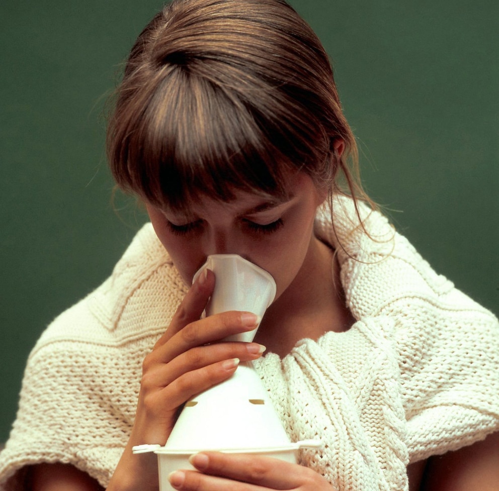 Eine junge Frau benutzt ein Inhalationsgerät