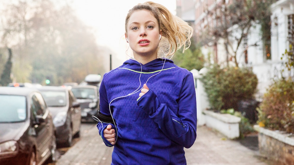 Eine junge Frau joggt auf einem Bürgersteig