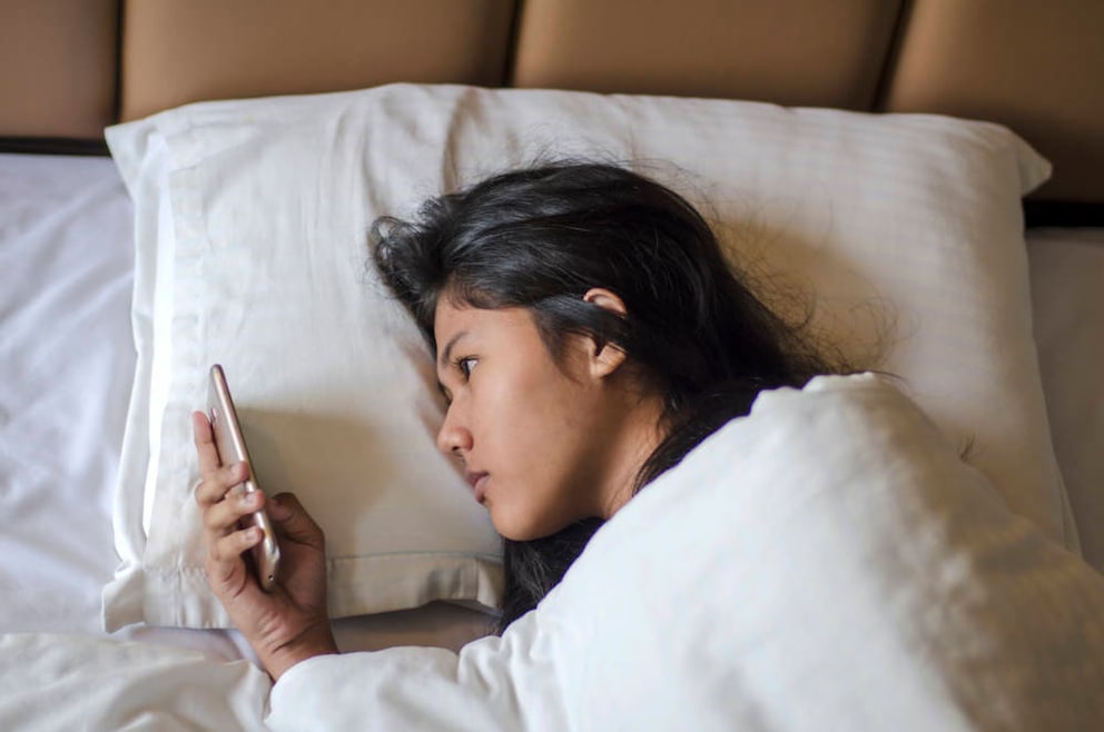 Teenager with phone in bed