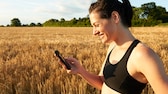 Eine sportliche Frau schaut auf ihr Smartphone