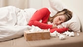 Erkältete Frau liegt im Bett und schläft