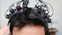 Viele Elektroden, befestigt auf einem Kopf mit schwarzen Haaren