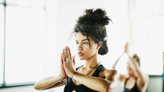Eine Frau in der Baum-Position während einer Yoga-Stunde