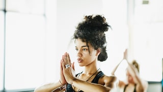 Eine Frau in der Baum-Position während einer Yoga-Stunde