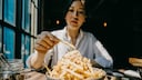 Junge Frau isst Pommes frites