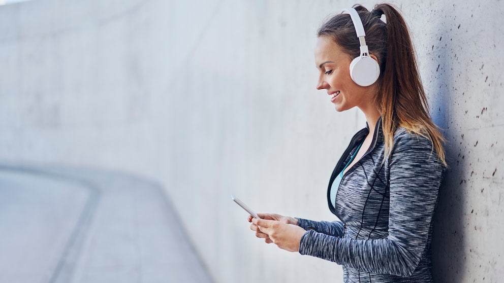 Eine sportliche Frau schaut auf ihr Handy