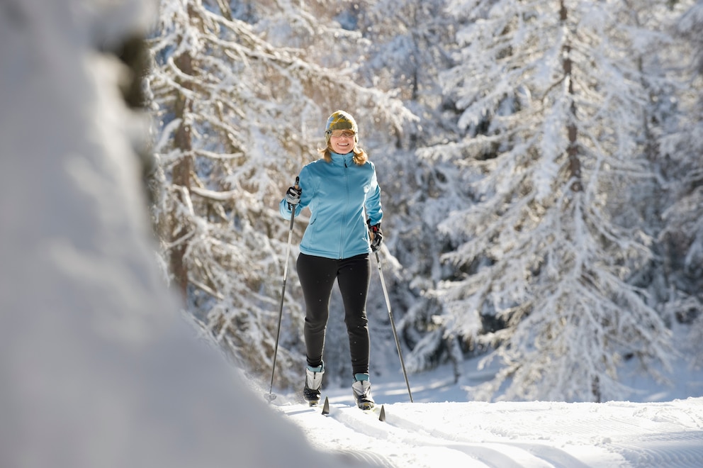 Eine Frau beim Skilanglauf im Wald