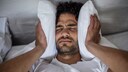 Mann leidet im Bett unter Lärmbelästigung