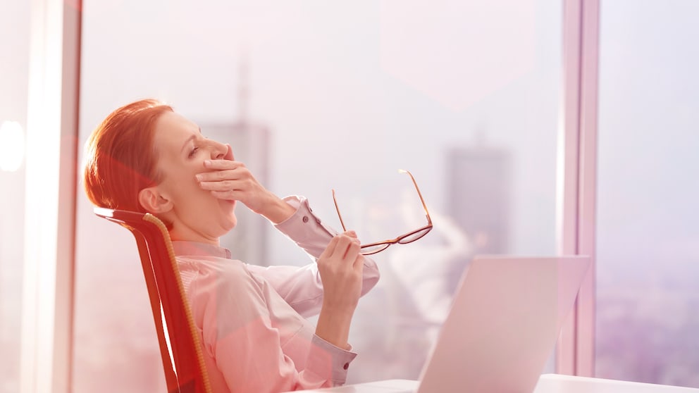 Eine Frau gähnt im Büro