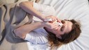 Eine Frau liegt im Bett und schnäuzt sich ins Taschentuch