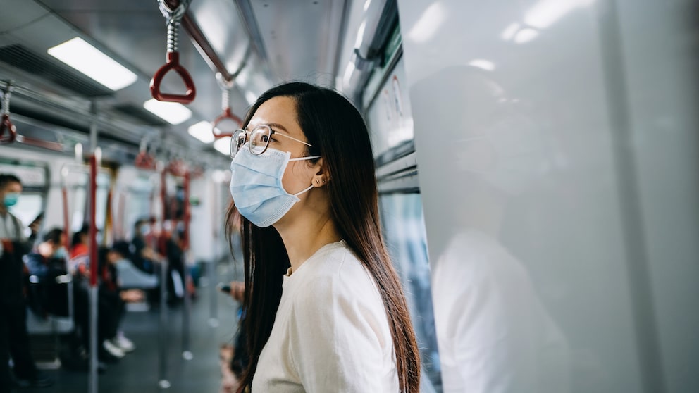 Eine junge Frau mit Atemschutzmaske in der U-Bahn