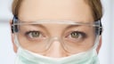 Frau tr&auml;gt Schutzbrille und Mundschutzmaske