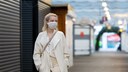 Anti-Corona-Maßnahmen: Eine junge Frau trägt eine Mund-Nasen-Schutzmaske und geht durch eine leere Fußgängerzone