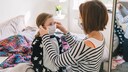 Mutter schützt Tochter mit Maske vor dem Coronavirus
