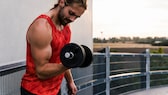 Junger Mann trainiert mit Dumbbell