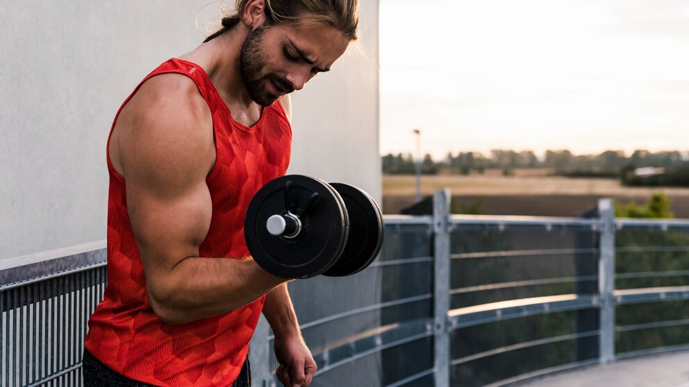 Junger Mann trainiert mit Dumbbell