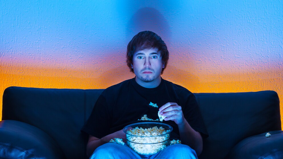Langes Fernsehen und dabei ungesunde Snacks essen – diese Kombination ist besonders schlecht für die Gesundheit.