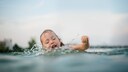 Ein Kind versucht sich beim Baden im See &uuml;ber Wasser zu halten