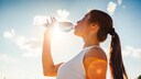 Evian: Frau trinkt Wasser aus einer Flasche