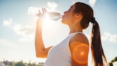 Evian: Frau trinkt Wasser aus einer Flasche