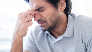 Mann hält sich bei Migräne-Attacke die Stirn
