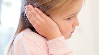 Mittelohrentzündung: Ein Mädchen hält sich das Ohr vor Schmerzen