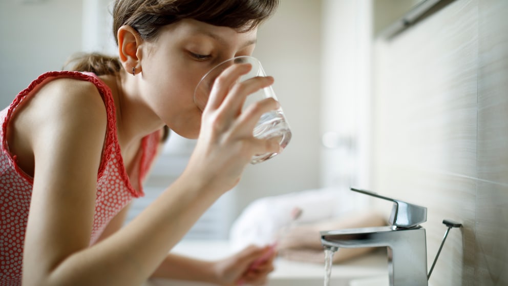 Gurgel-Test Corona: Ein Mädchen nimmt einen Schluck Wasser zum Gurgeln