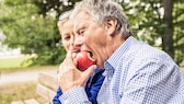 Mann beißt in einen Apfel