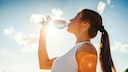 Frau mit Wasserflasche – wie viel sollte man beim Sport trinken?