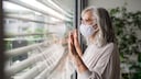 Frau mit Mundschutz am Fenster