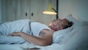 Ein Mann mittleren Alters liegt schlaflos im Bett
