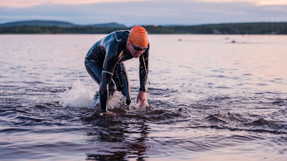 Ein Mann im Neoprenanzug steigt nach dem Schwimmen aus dem See