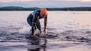 Ein Mann im Neoprenanzug steigt nach dem Schwimmen aus dem See