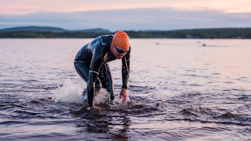 Ein Mann im Neoprenanzug steigt nach dem Schwimmen aus dem See