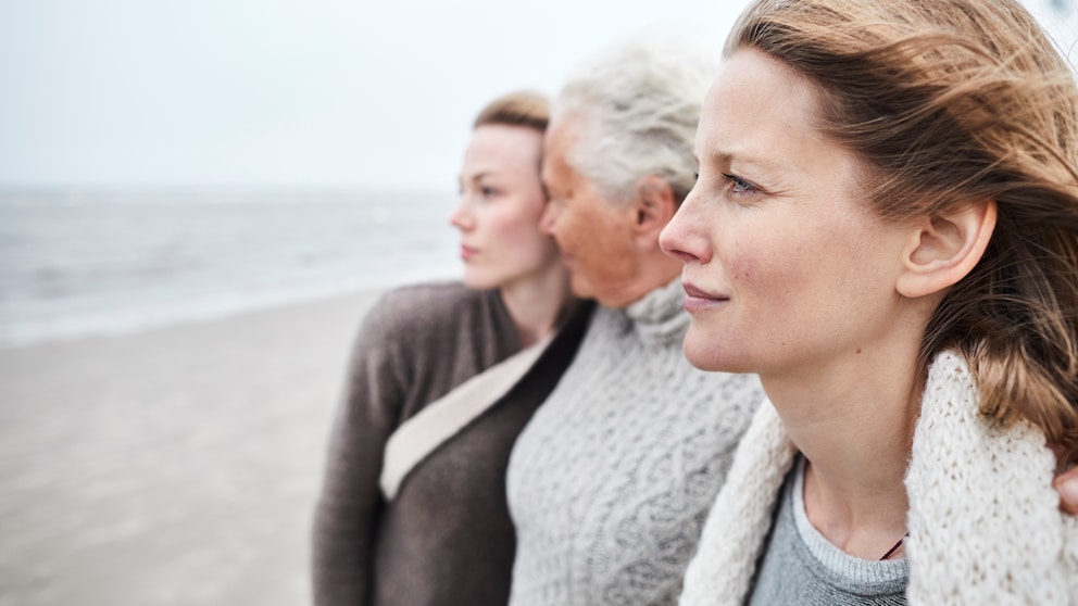 Zwei junge Frauen gehen mit ihrer Mutter am Strand spazieren