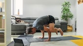 Ein Mann führt im Wohnzimmer eine Yoga-Pose aus