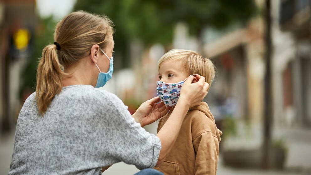 Eine Frau zieht einem Jungen eine Maske auf