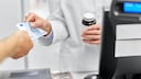 Medikamente zuzahlen: Eine Frau bezahlt in einer Apotheke für ein Medikament