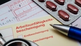 Krankmeldung verspätet Krankenkasse: Auf einer Arbeitsunfähigkeitsbescheinigung liegen ein Stift, Tabletten und ein Rezept