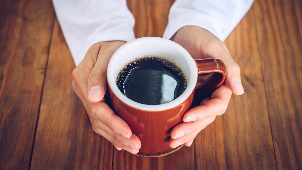 Kaffee Leber: Ein Mann hält eine Tasse Kaffe in seinen Händen