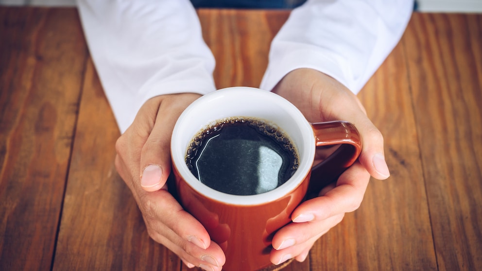 Kaffee Leber: Ein Mann hält eine Tasse Kaffe in seinen Händen